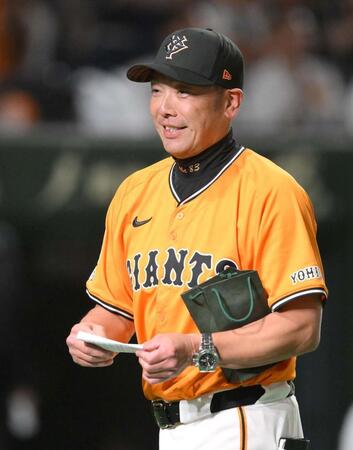 　試合前のメンバー表交換時に新庄監督から深緑の紙袋を受け取った阿部監督（撮影・伊藤笙子）