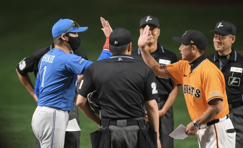 試合前のメンバー表交換を終え、ハイタッチする新庄監督（左）と阿部監督（撮影・伊藤笙子）