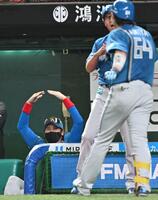 　４回、ソロ本塁打を放った田宮（６４）を迎える新庄監督（左）