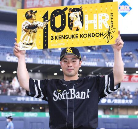 　通算１００号を達成し、記念ボードを掲げる近藤（撮影・立川洋一郎）