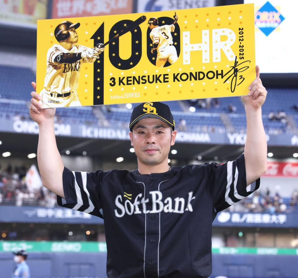 　通算１００号を達成し、記念ボードを掲げる近藤（撮影・立川洋一郎）