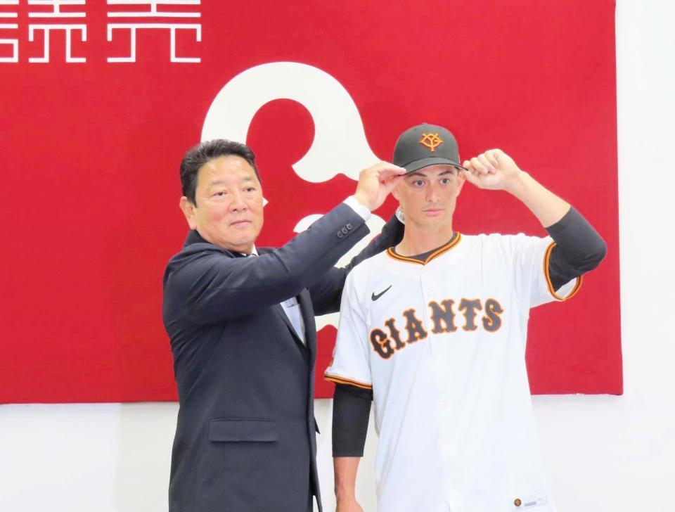 　入団会見を行い、吉村本部長から帽子をかぶせてもらう乙坂（撮影・中田康博）