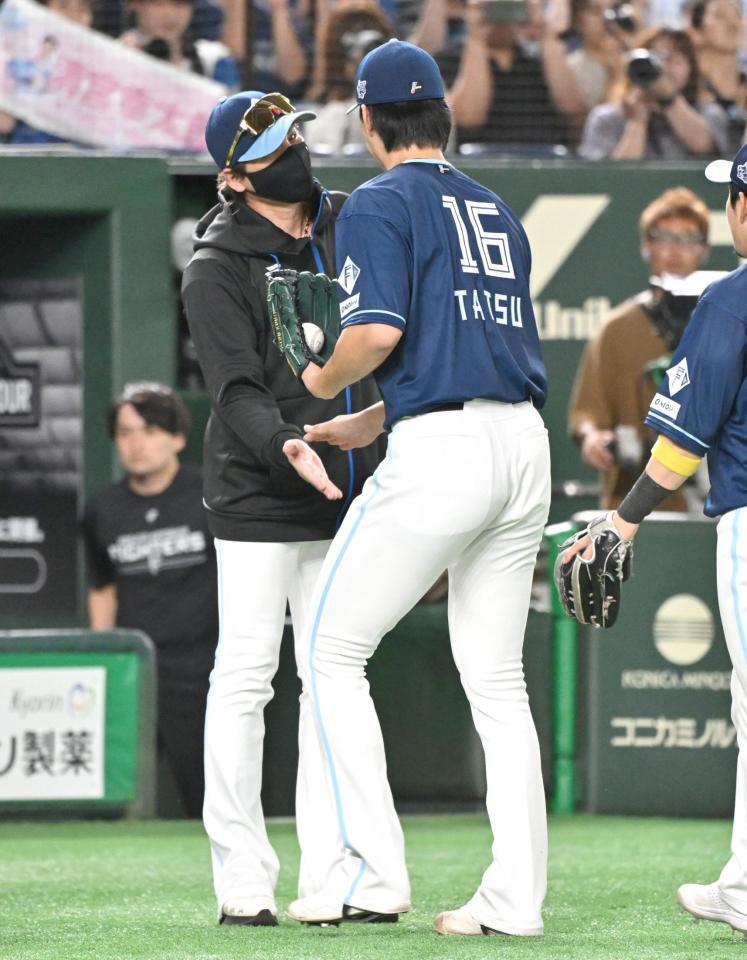 　完投勝利の達とタッチを交わす新庄監督