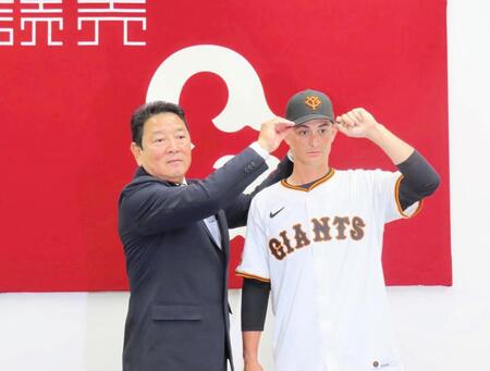 　入団会見を行い、吉村本部長から帽子をかぶせてもらう乙坂＝１３日