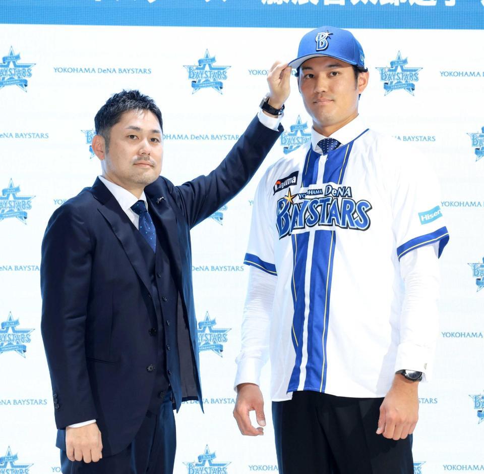 　萩原龍大チーム統括本部長（左）に帽子をかぶせてもらう藤浪