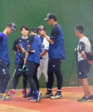 　ブルペンでの投球練習後、データを確認する藤浪（右）