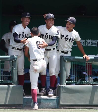 　７回、吉野颯真の同点適時内野安打で生還した大阪桐蔭・宮本楽久（６）を迎える中野大虎（中央）＝撮影・中田匡峻