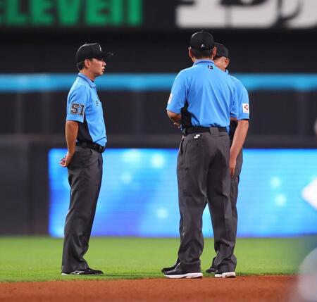 　６回、スプリンクラーが誤作動し、話をする審判団（撮影・中島達哉）