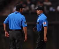 　６回、スプリンクラーが誤作動し、話をする審判団（撮影・中島達哉）