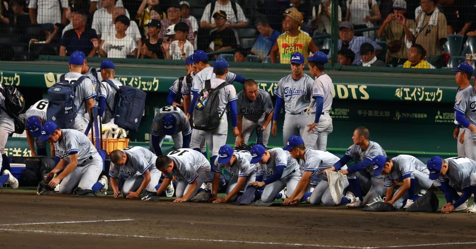 　初戦敗退しベンチ前で甲子園の土を拾う小松大谷ナイン（撮影・山口登）