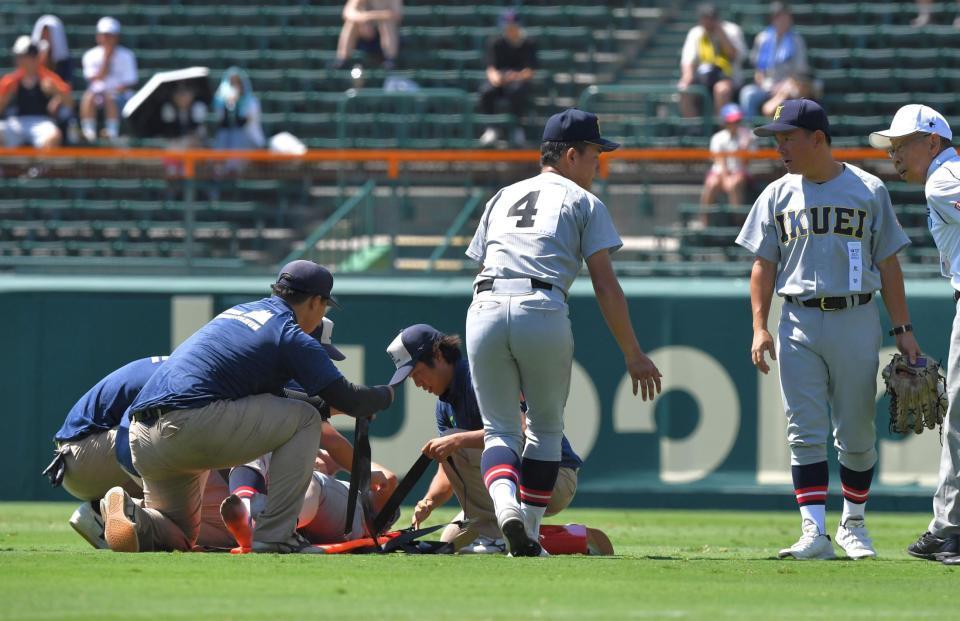　８回裏終了後もベンチへ戻れず、担架で運ばれる仙台育英・田山纏。右は須江監督（撮影・出月俊成）
