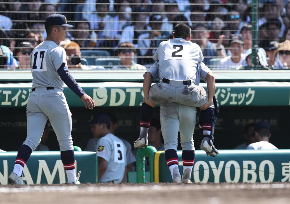 　７回裏終了後、足を痛め、背負われてベンチに引き揚げる仙台育英の捕手川尻