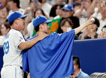 　プロ初勝利を挙げた金丸は井上監督に激励されながら、家族が見守るスタンドへボールを掲げる（撮影・田中太一）