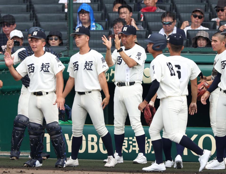 　３回裏の守備を終えたナインを迎える西日本短大付・西村慎太郎監督（中央）＝撮影・中田匡峻