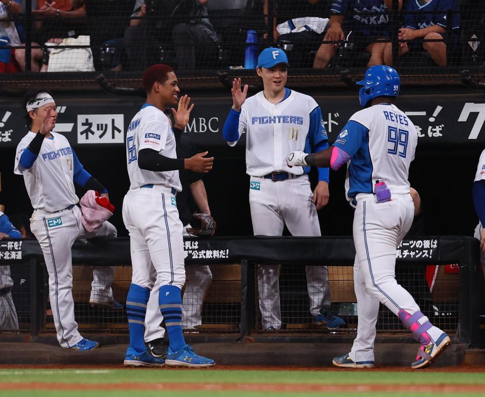 　８回、同点ソロを放ったレイエス（９９）を迎える山崎（中央右）ら日本ハムナイン（撮影・中島達哉）