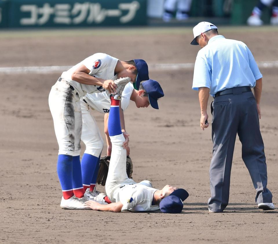 　８回、横浜・阿部葉太の打球を後逸した直後に足がつり倒れる綾羽の二塁手・経免拓隼（下）＝撮影・開出牧