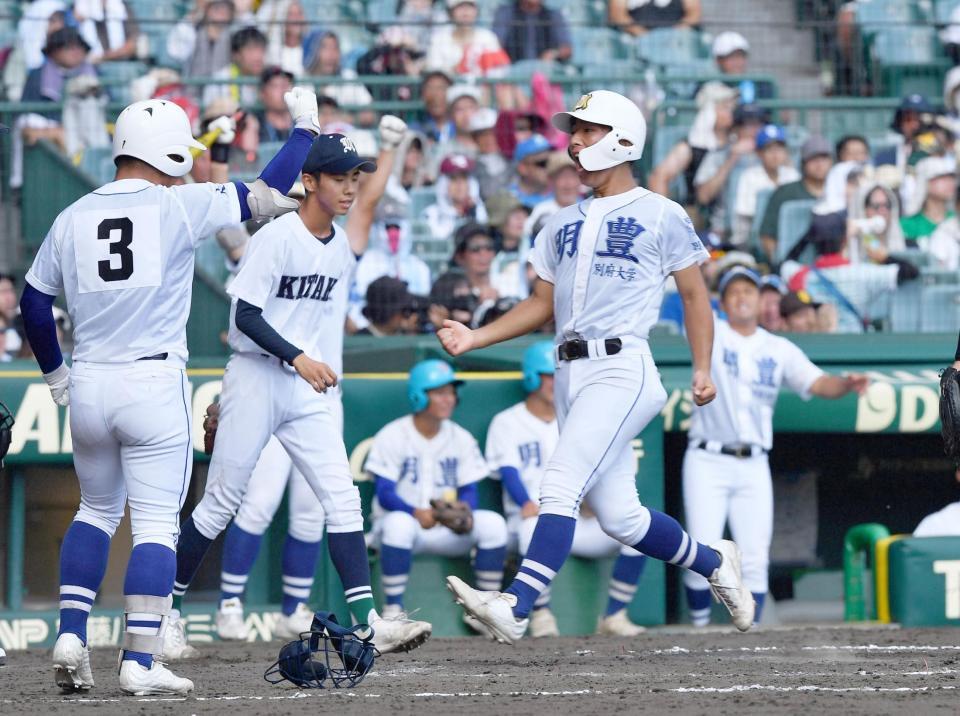 　５回、辻田拓未の中越え先制二塁打で一塁から生還しガッツポーズを決める明豊・林亮佑（右手前）。後方左は佐賀北・稲富理人（撮影・開出牧）