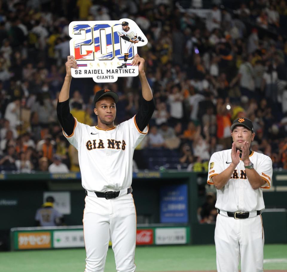 　通算２００セーブを達成し、阿部監督（右）に祝福されながらボードを掲げるマルティネス（撮影・西岡正）