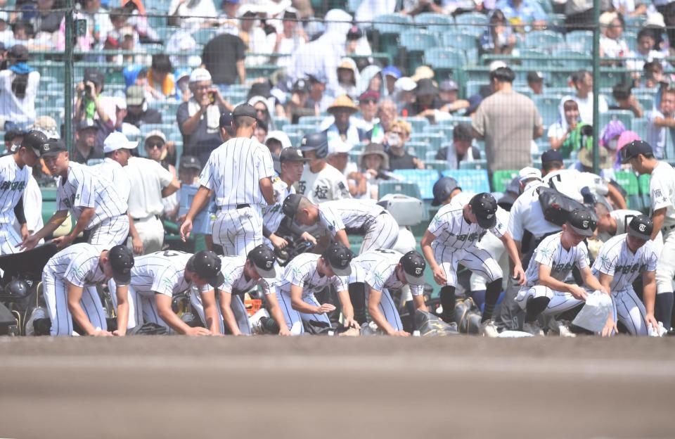 　３回戦で敗退し甲子園の土を拾う津田学園ナイン（撮影・開出牧）