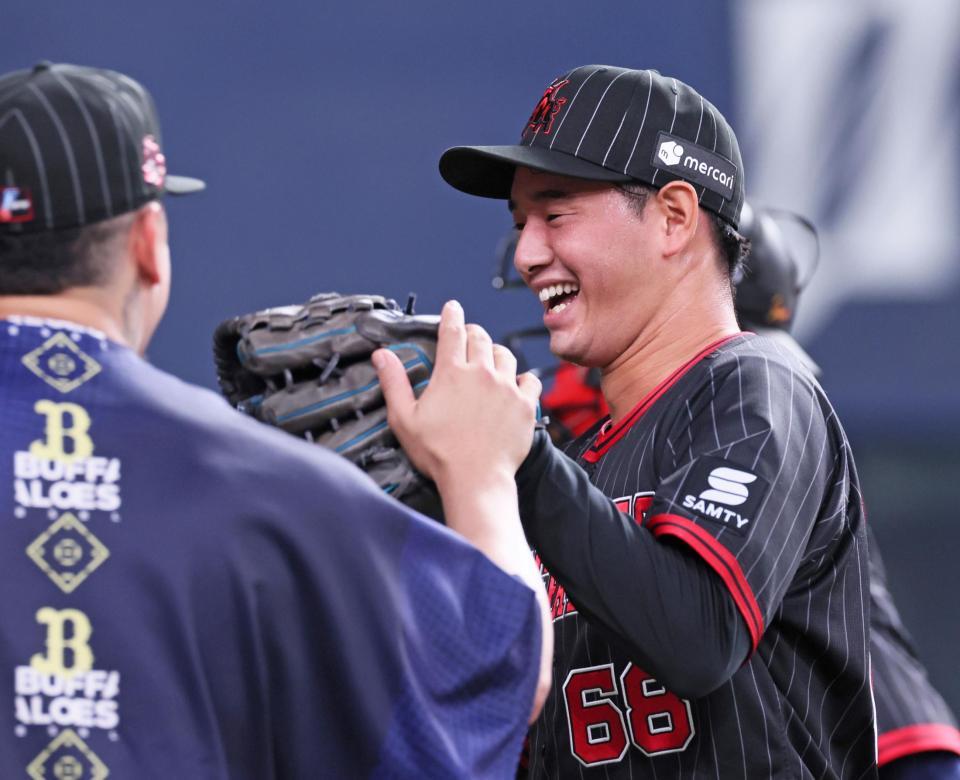 　１１回表に登板して無失点に抑えナインの出迎えに笑顔を見せる入山（撮影・立川洋一郎）