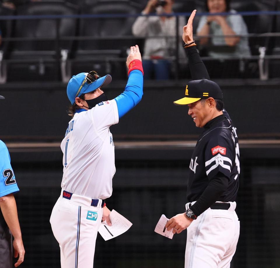 　メンバー表を交換し、小久保監督（右）と豪快にハイタッチを交わす新庄監督（撮影・中島達哉）