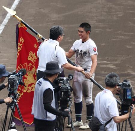 　笑顔で優勝旗を受け取る沖縄尚学・真喜志拓斗（右）＝撮影・中田匡峻