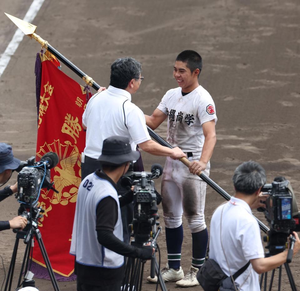 　笑顔で優勝旗を受け取る沖縄尚学・真喜志拓斗（右）＝撮影・中田匡峻