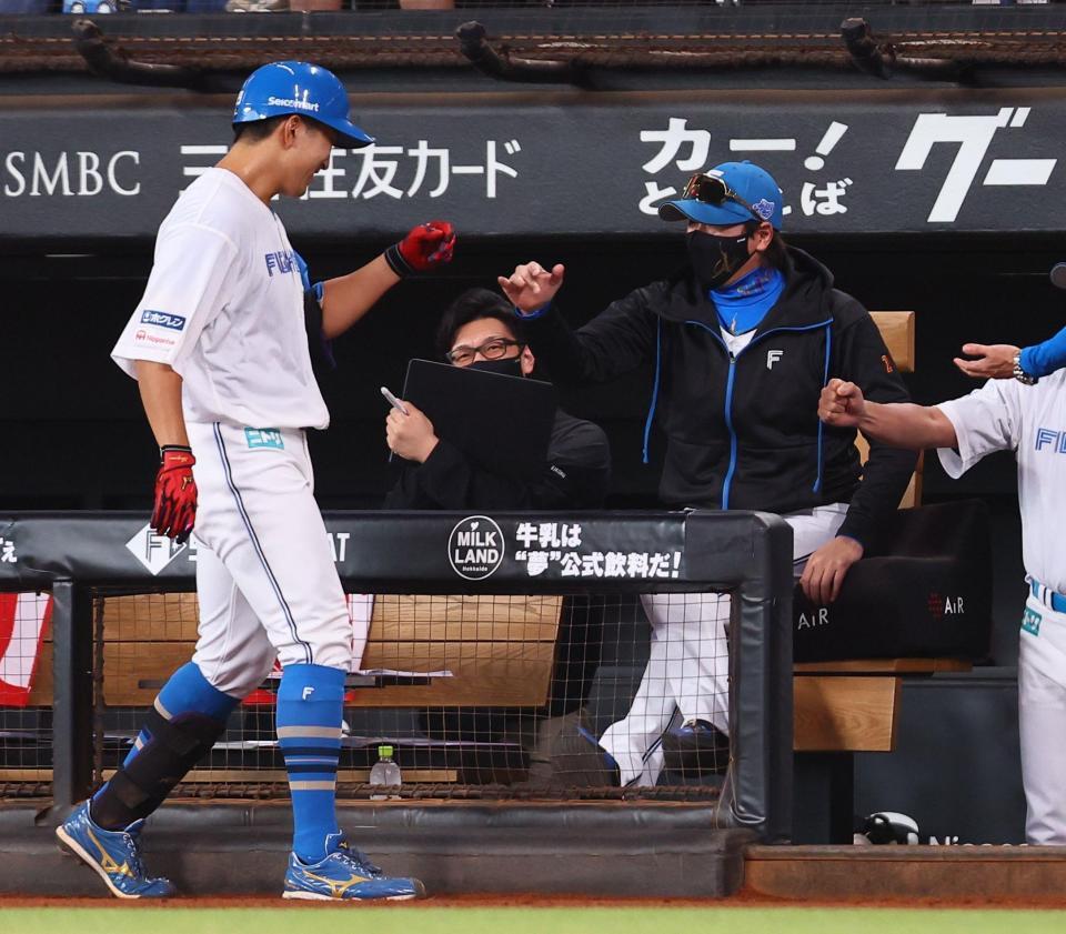 　１回、勝ち越し犠飛を放った有薗（左）を迎える新庄監督（撮影・中島達哉）