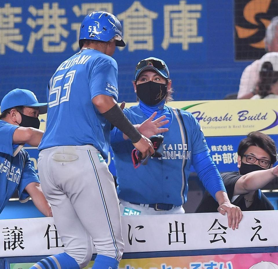 ６回、山縣の右前適時打で二塁から生還した水谷（左）とタッチを交わす新庄監督（撮影・開出牧）