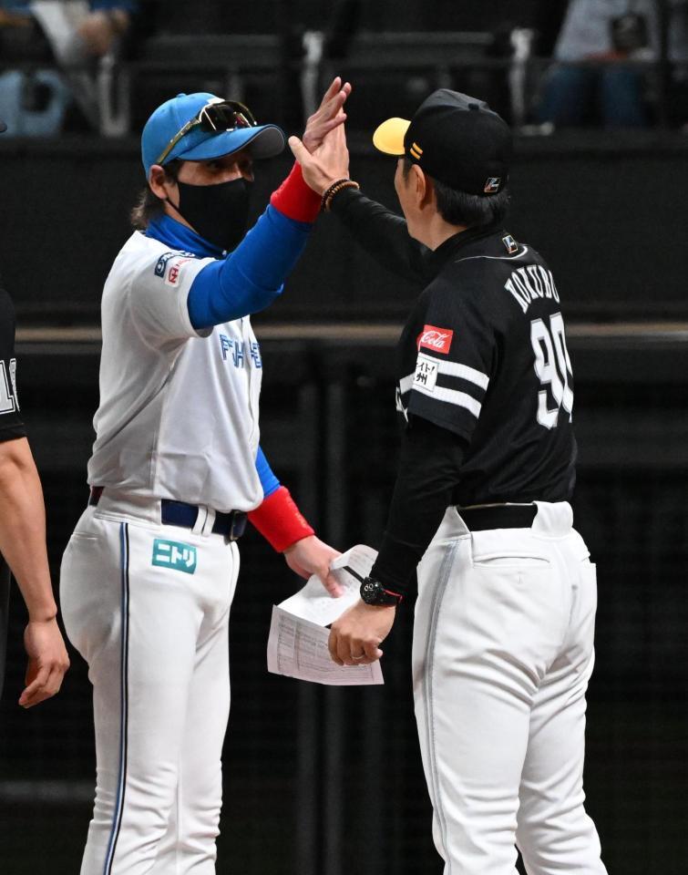 　メンバー表を交換しタッチを交わす小久保監督（右）と新庄監督