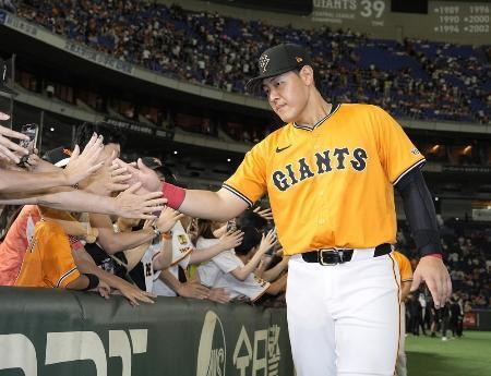 　ファンとタッチを交わす巨人・岡本＝８月東京ドーム