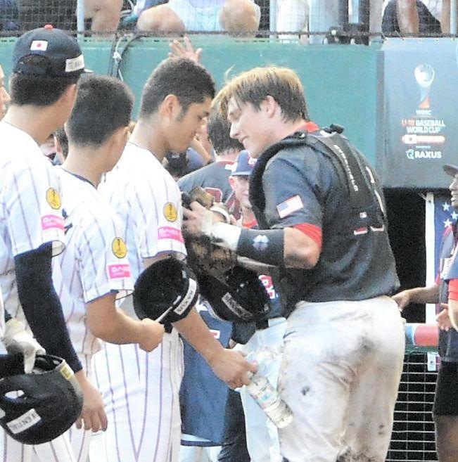 　米国の選手に道具を手渡す阿部