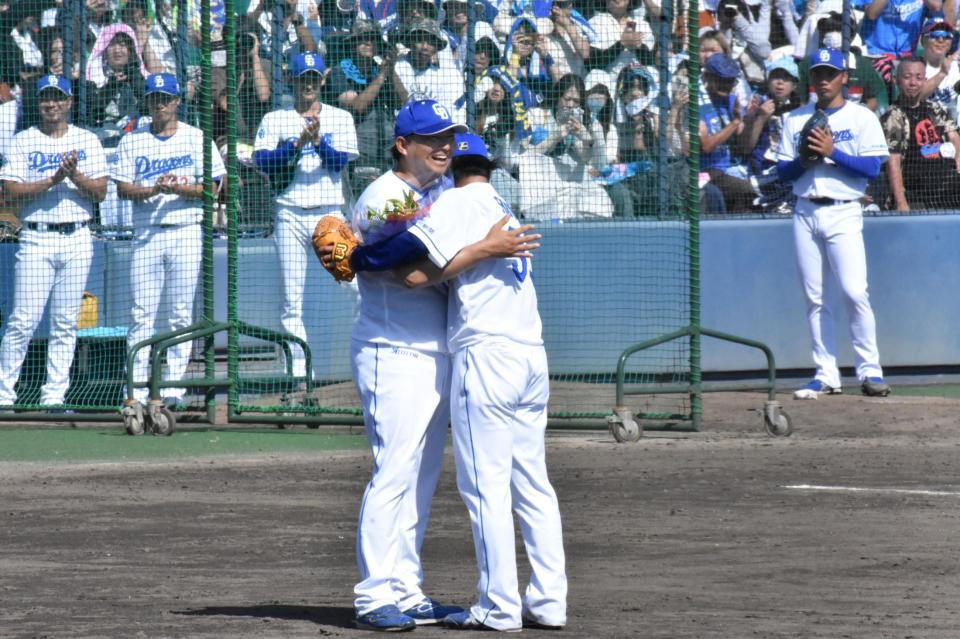 　花束を受け取り、田島投手コーチと抱き合う祖父江（右）