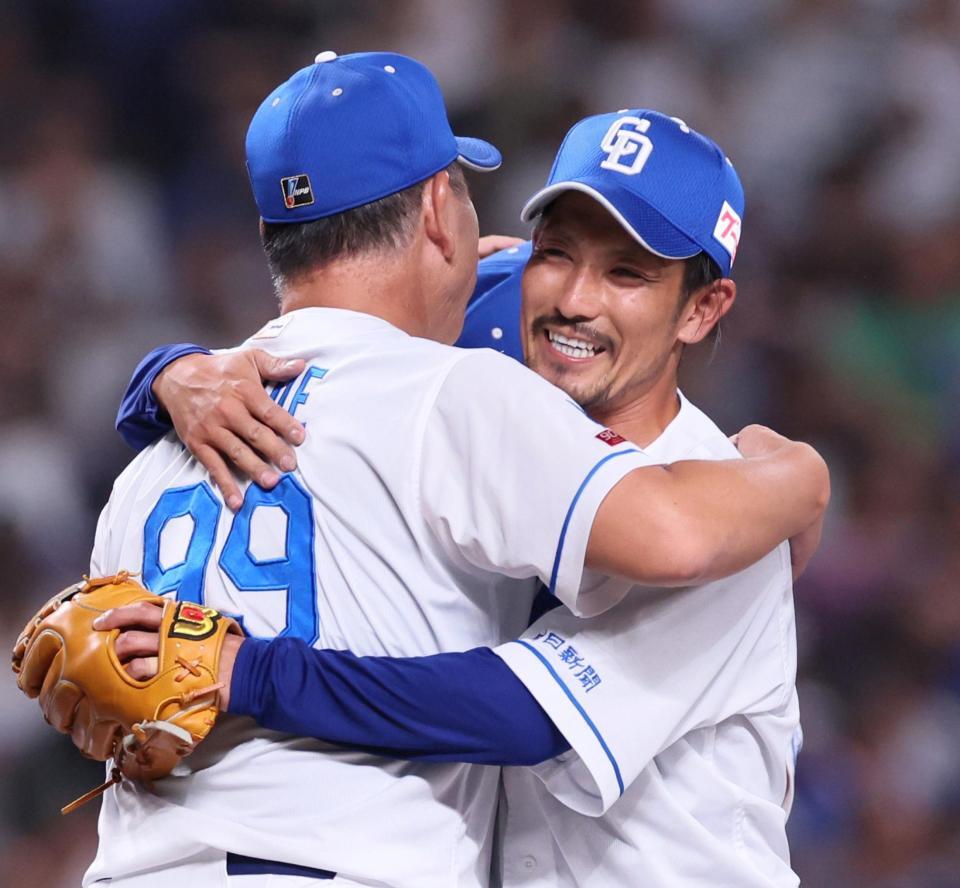 　８回、ラスト登板を終え井上監督（左）と抱擁を交わす祖父江（撮影・立川洋一郎）