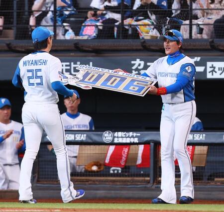 　５回、９００試合登板を達成した宮西（２５）に記念ボードを手渡す新庄監督（撮影・中島達哉）