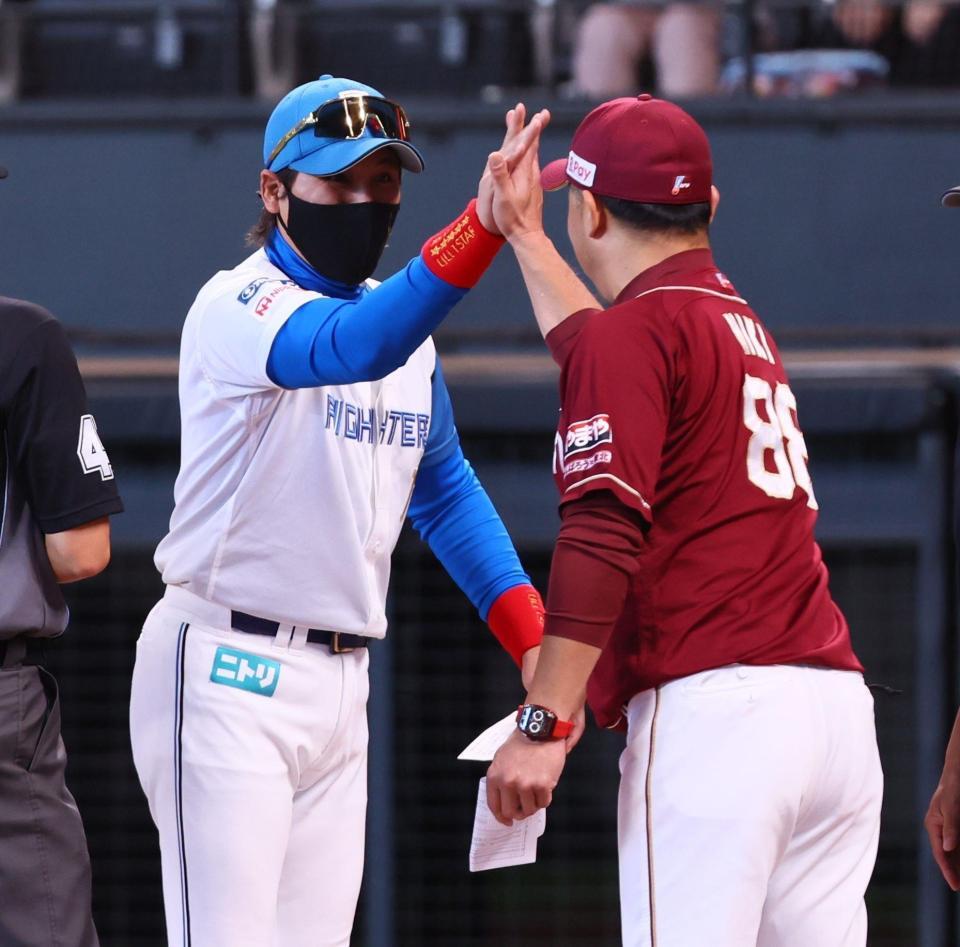 　メンバー表を交換し、三木監督（右）とハイタッチを交わす新庄監督（撮影・中島達哉）