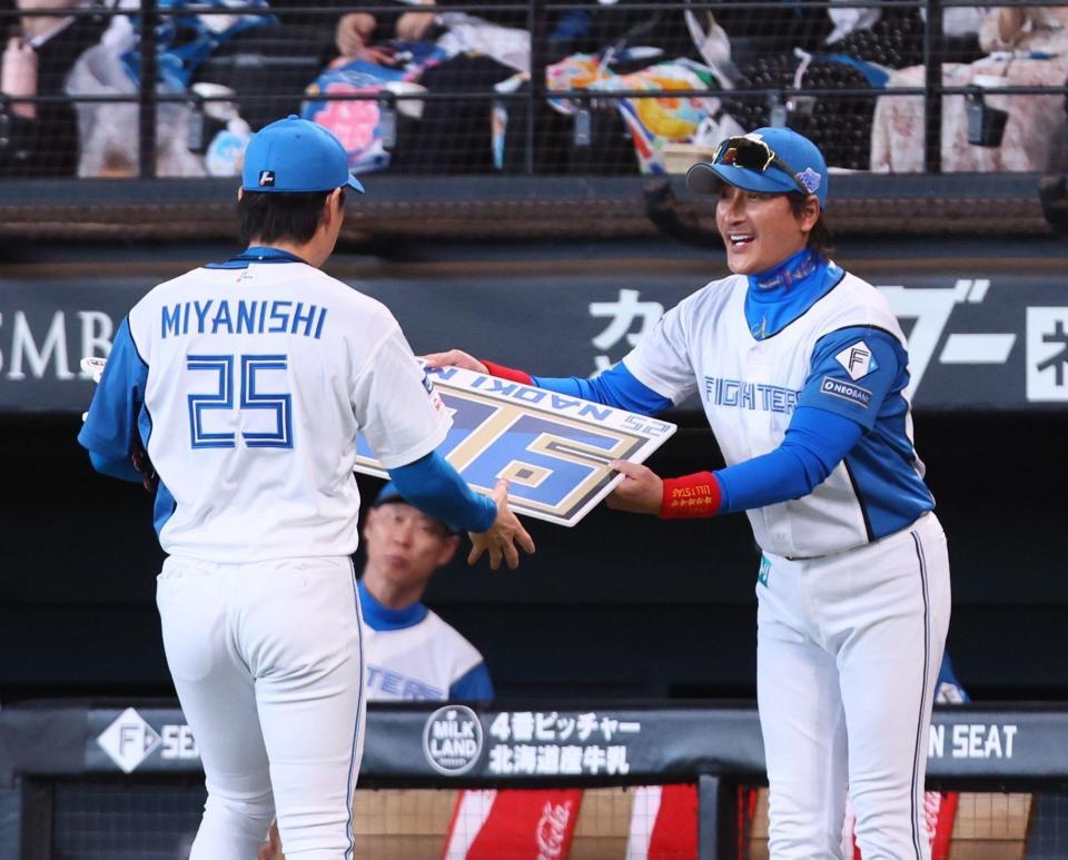 　５回、９００試合登板を達成した宮西（２５）に記念ボードを手渡す新庄監督（撮影・中島達哉）