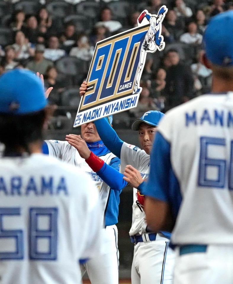 　通算９００試合登板を達成し、記念のボードを掲げる宮西