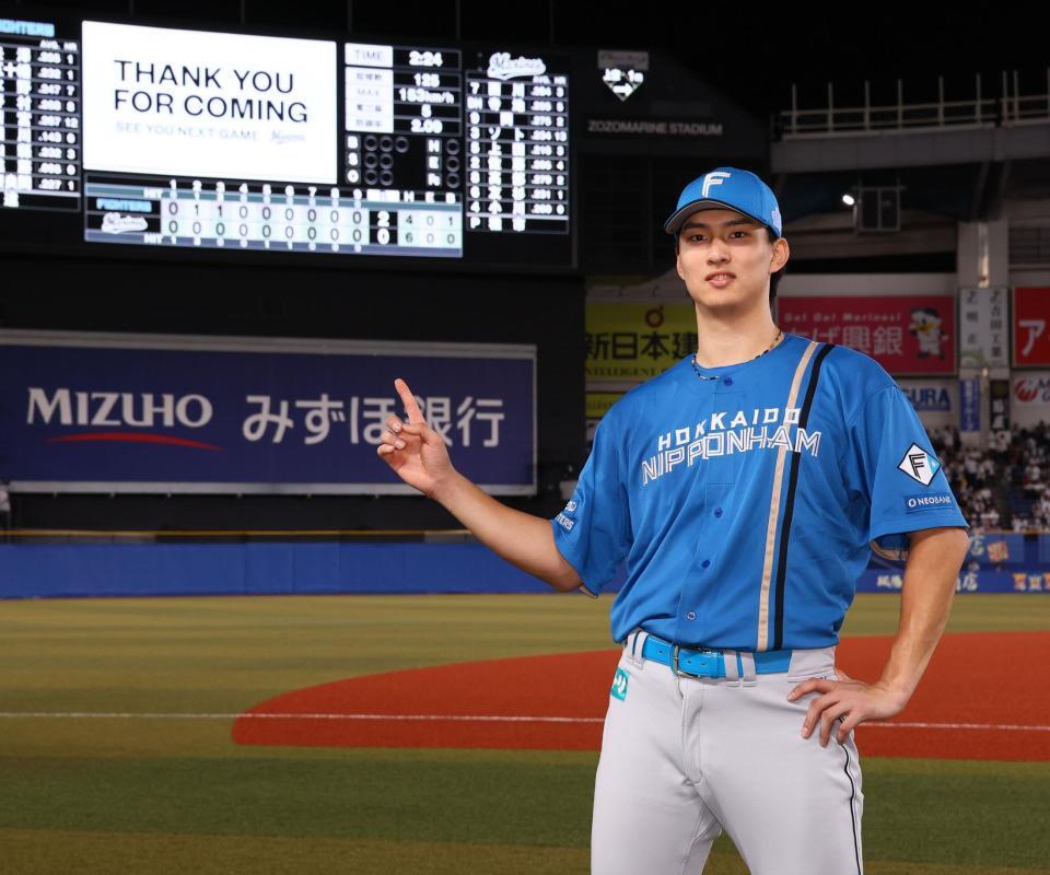 　プロ初完封勝利をあげたスコアボードを指さし、記念撮影に応じる達（撮影・中島達哉）