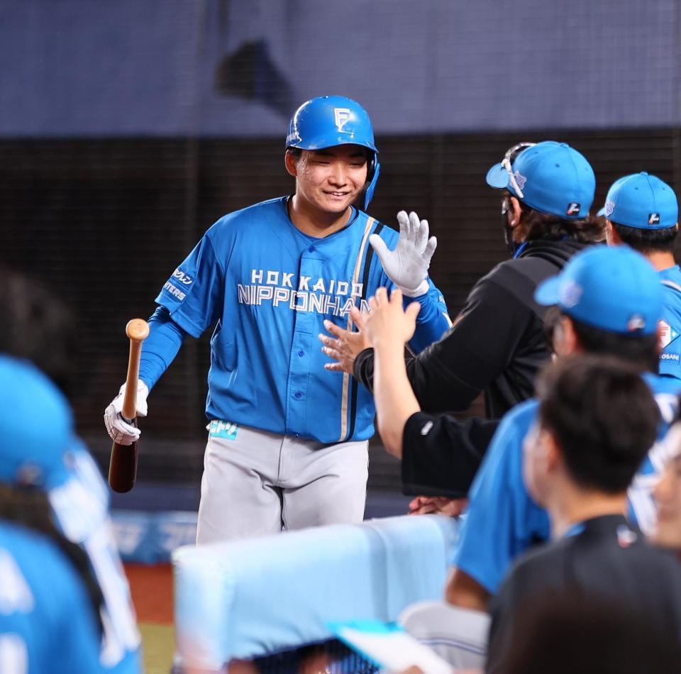 　８回、勝ち越し犠飛を放ち、新庄監督（右から２人目）に迎えられる山県（撮影・中島達哉）