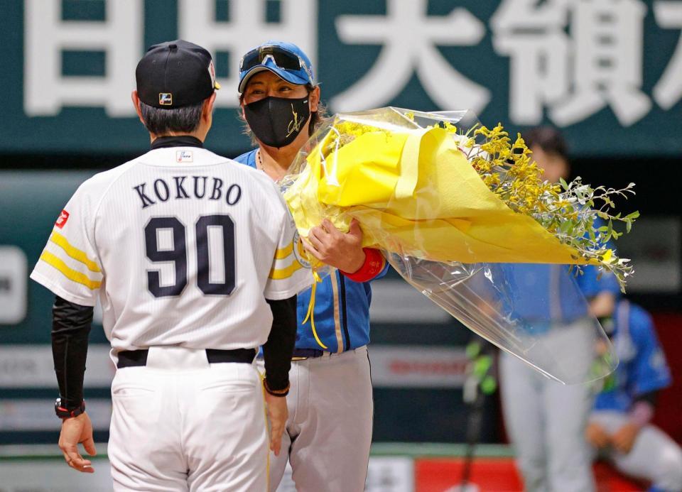 　試合前のメンバー表交換で、小久保監督（手前）に花束を贈る新庄監督