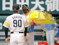 　試合前のメンバー表交換で小久保監督（手前）に花束を贈る新庄監督