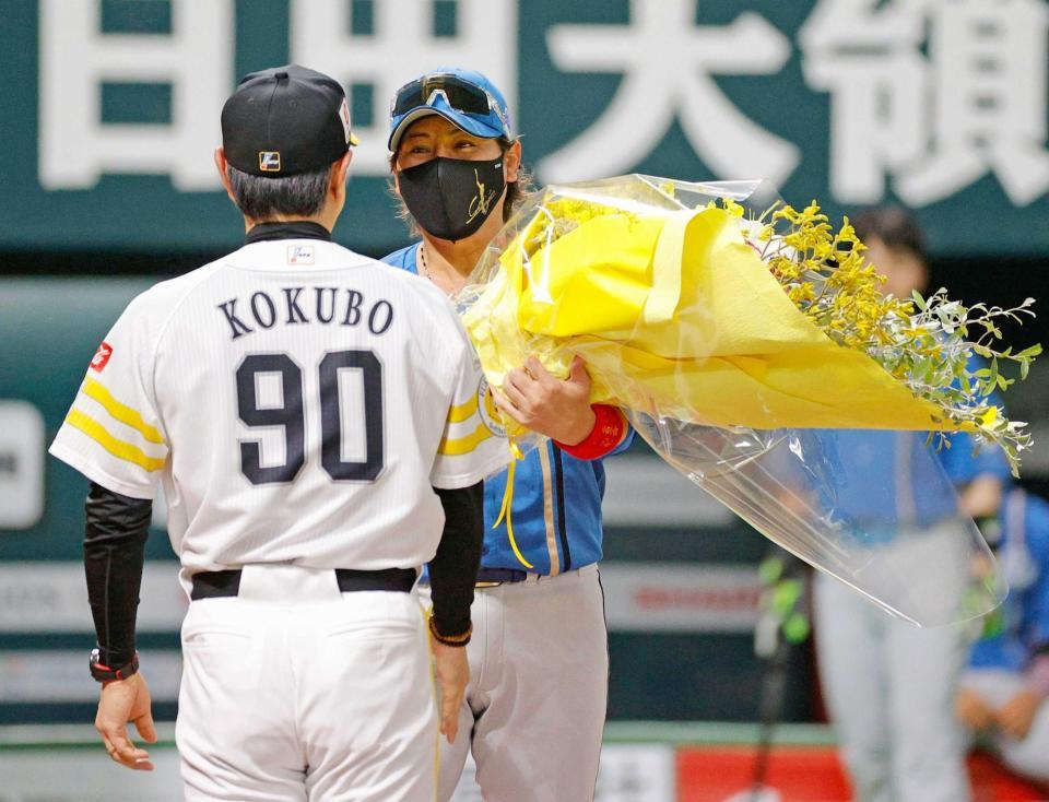 　試合前のメンバー表交換で小久保監督（手前）に花束を贈る新庄監督