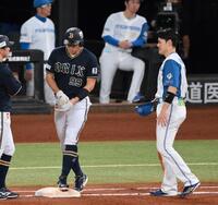 　６回、死球を受けた左腕にテーピングを巻き一塁へ向かう杉本（左）に頭を下げる一塁手の清宮幸（撮影・伊藤笙子）