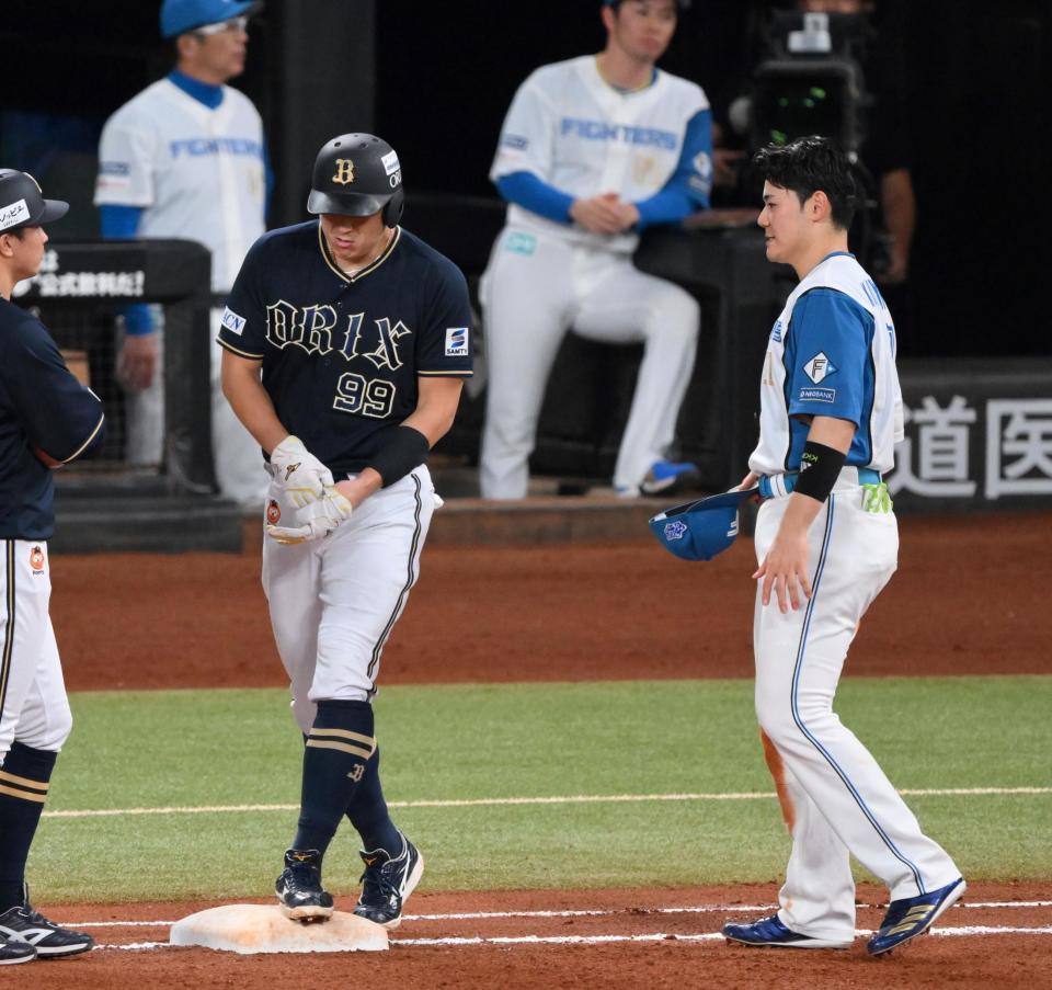 　６回、死球を受けた左腕にテーピングを巻き一塁へ向かう杉本（左）に頭を下げる一塁手の清宮幸（撮影・伊藤笙子）