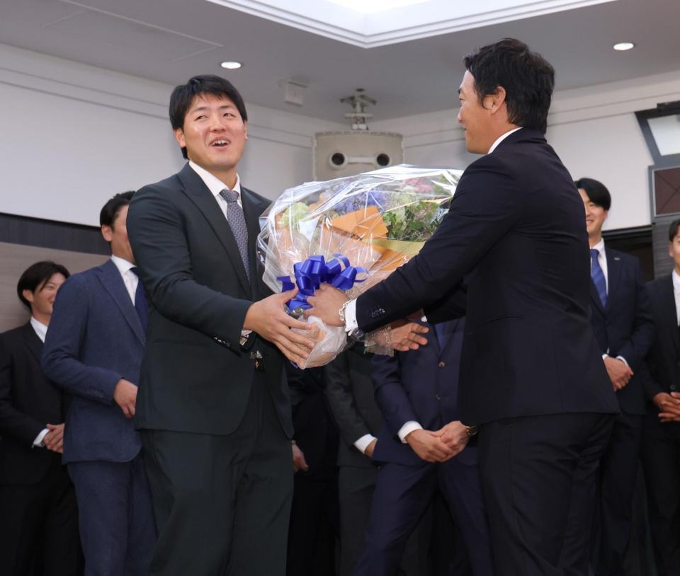 　長野（右）から花束を渡されて困惑する岡本（撮影・西岡正）