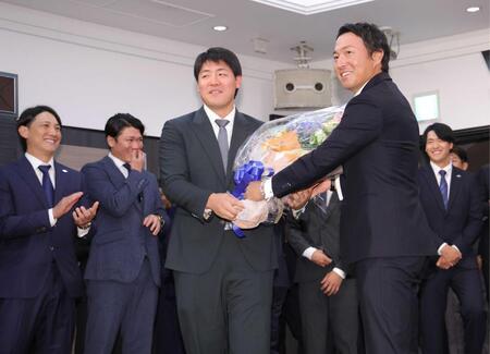 　困惑する岡本（手前左）に花束を渡す