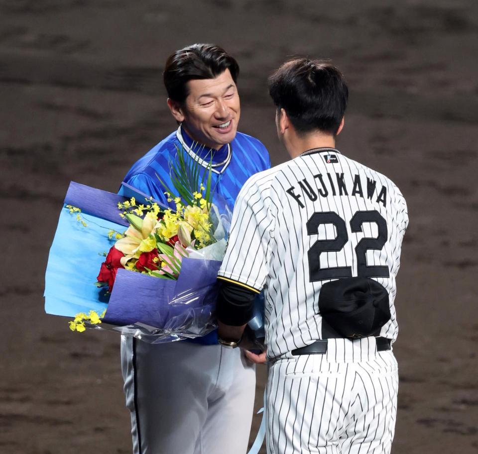 　三浦監督は藤川監督から花束を贈られ笑顔を見せる＝１７日