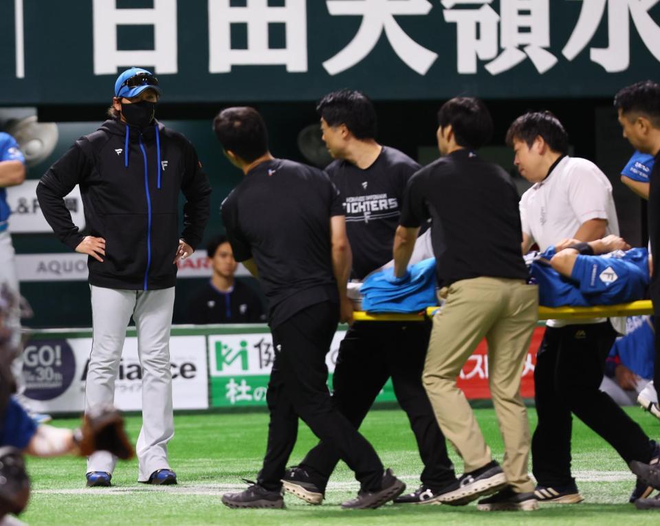 　１回、担架で運ばれる山県（右）と心配そうな表情で見つめる新庄監督（撮影・中島達哉）