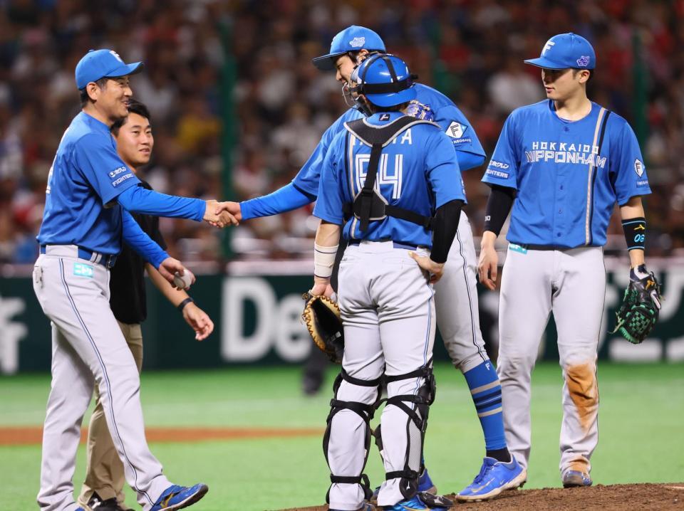 　５回、牧原大を迎えたところで交代となり、加藤投手コーチ（左）と握手を交わす古林（中央奥）＝撮影・中島達哉